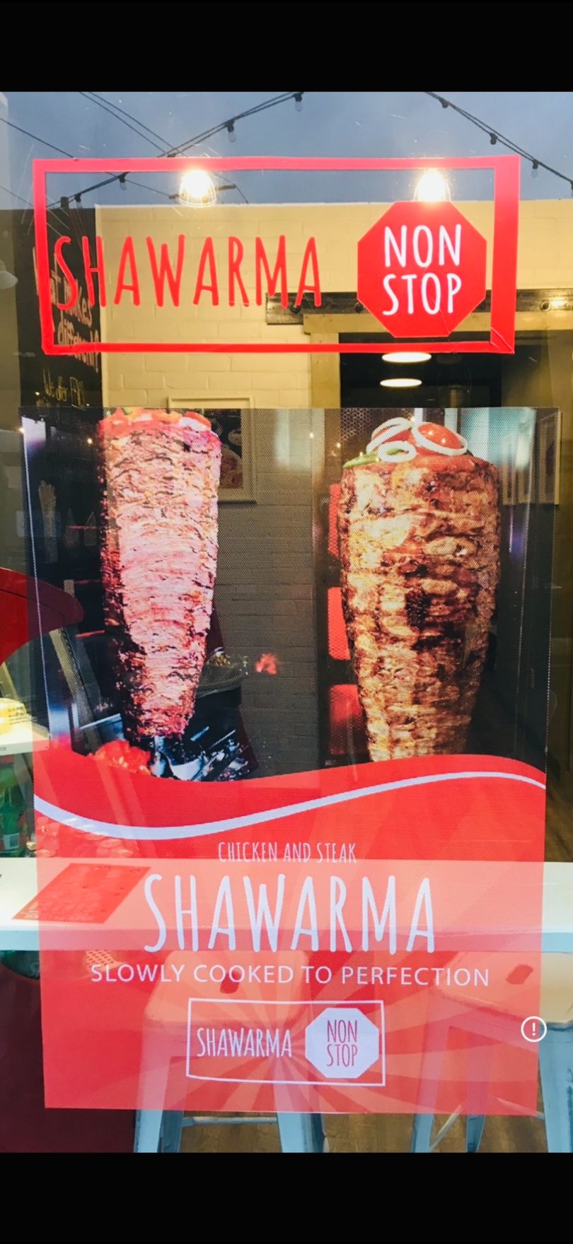 Restaurant window display advertising "Shawarma Non Stop" with images of two large shawarma spits.